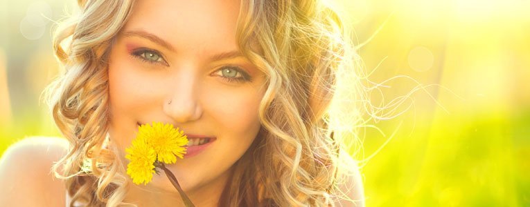 Woman smiling holding a flower using Sunsafe Rx